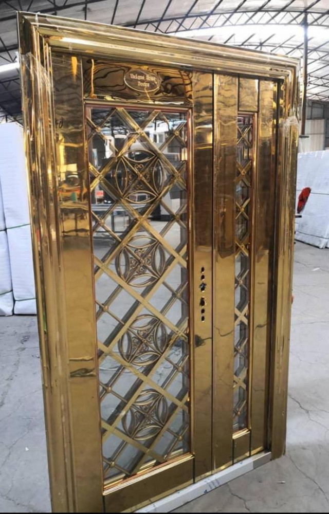 Luxurious ornate gold-finished elevator door with glass panels and intricate crisscross pattern