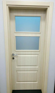 Interior door featuring two rectangular frosted glass panes in the upper half nd recessed panels in the lower half