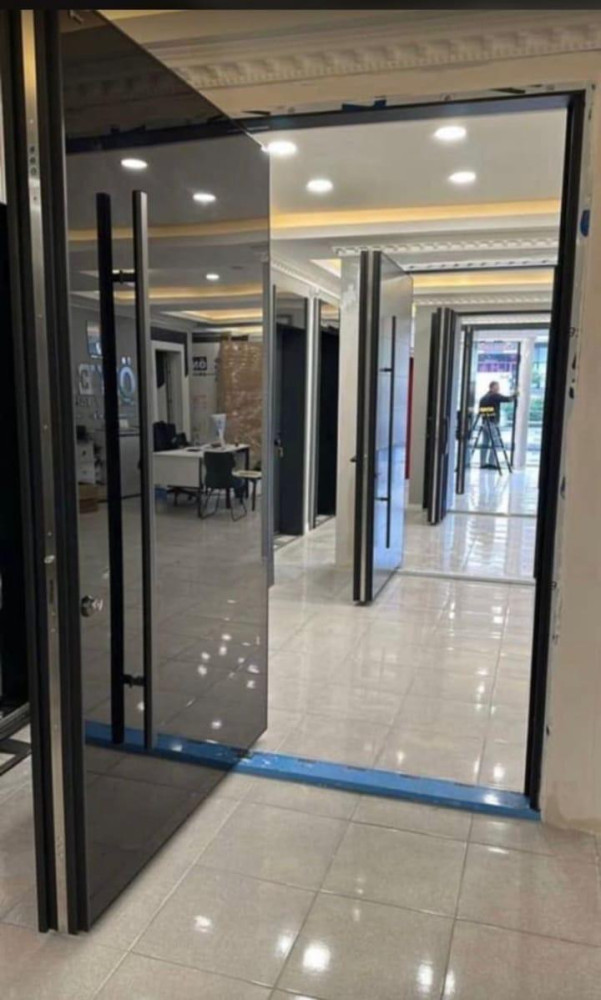 features a modern pivot door systems with a sleek, metalic finish and long vertical handles