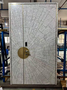 this double entrance door features a decorative sunburst design made from polished ston tiles and a prominent brass biometric handle