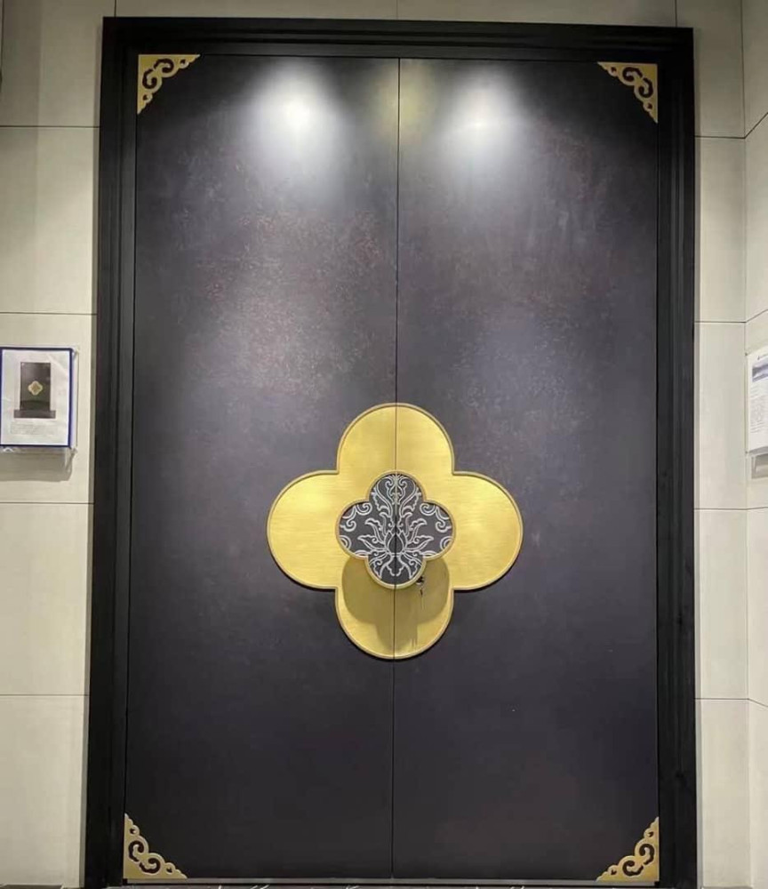 Modern, minimalist double door featuring decorative brass hardware with a quatrefoil shape and intricate engraved patterns