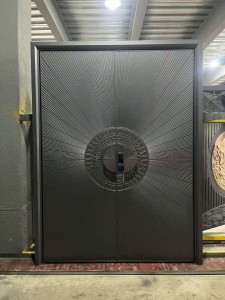 Modern cast aluminum or steel double security entry door featuring a distinctive radial sunburst design